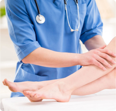 Médico examinando a perna de uma paciente durante consulta de tratamento vascular.